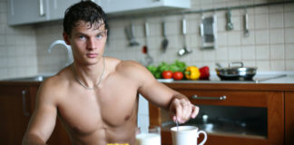 Shirtless man sitting in the kitchen