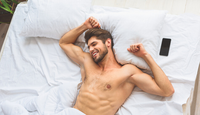 Shirtless guy in bed happy